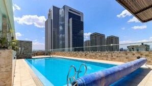 A rooftop pool with a view of a Marriott hotel building in the background. - Elite Residence View Palace Apartment (Nairobi)