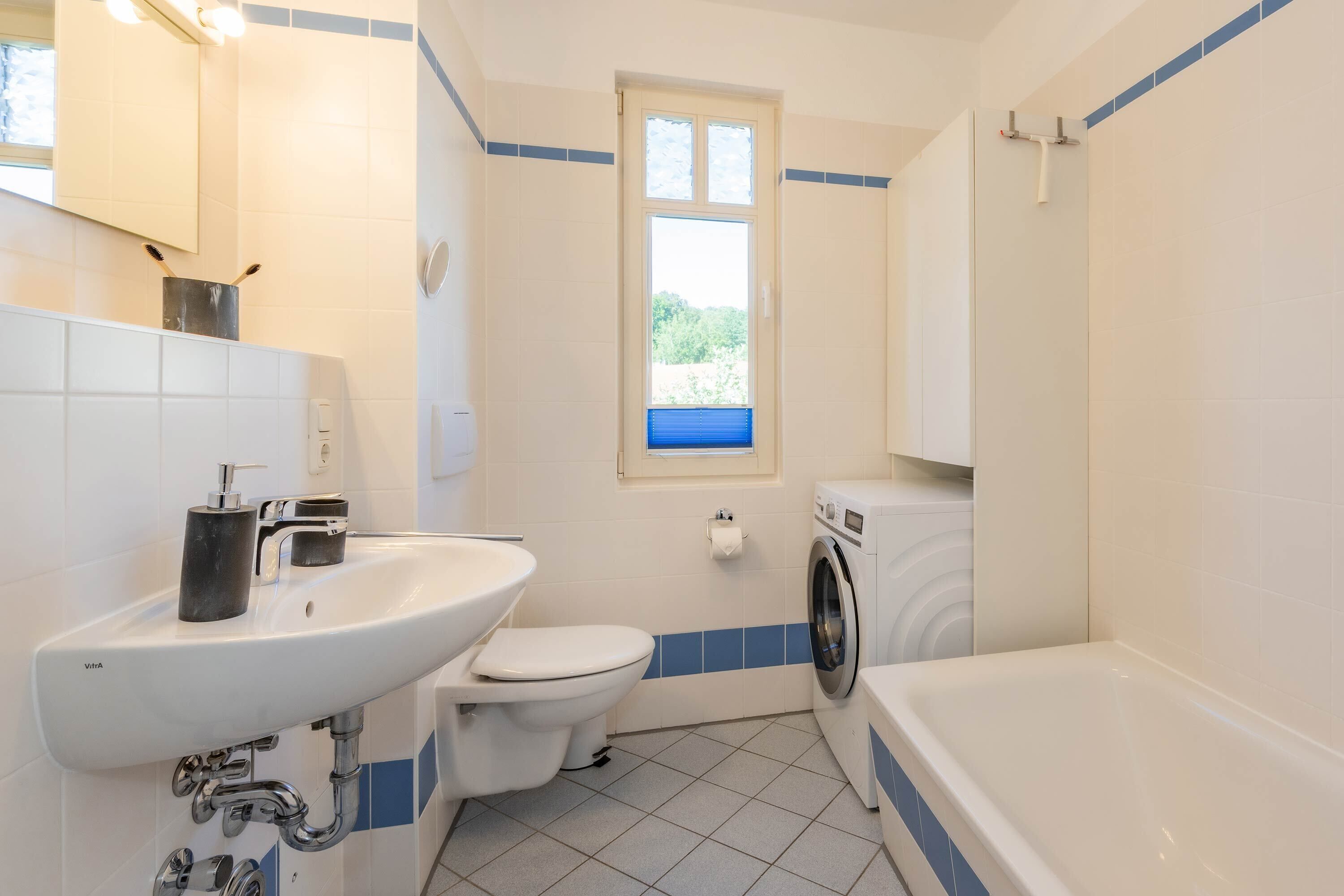 Un baño con lavamanos, inodoro, lavadora y bañera.