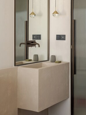 Un baño moderno con un espejo grande, un lavabo, dos lámparas colgantes y un perchero para toallas.