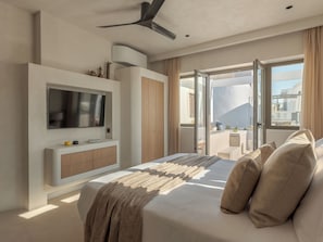 Een moderne slaapkamer met een bed, televisie en balkon met uitzicht.