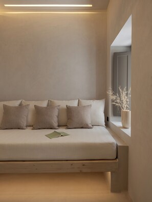 A minimalist bedroom with a bed, pillows, a window, and a plant. - Sifneos House (Paros)