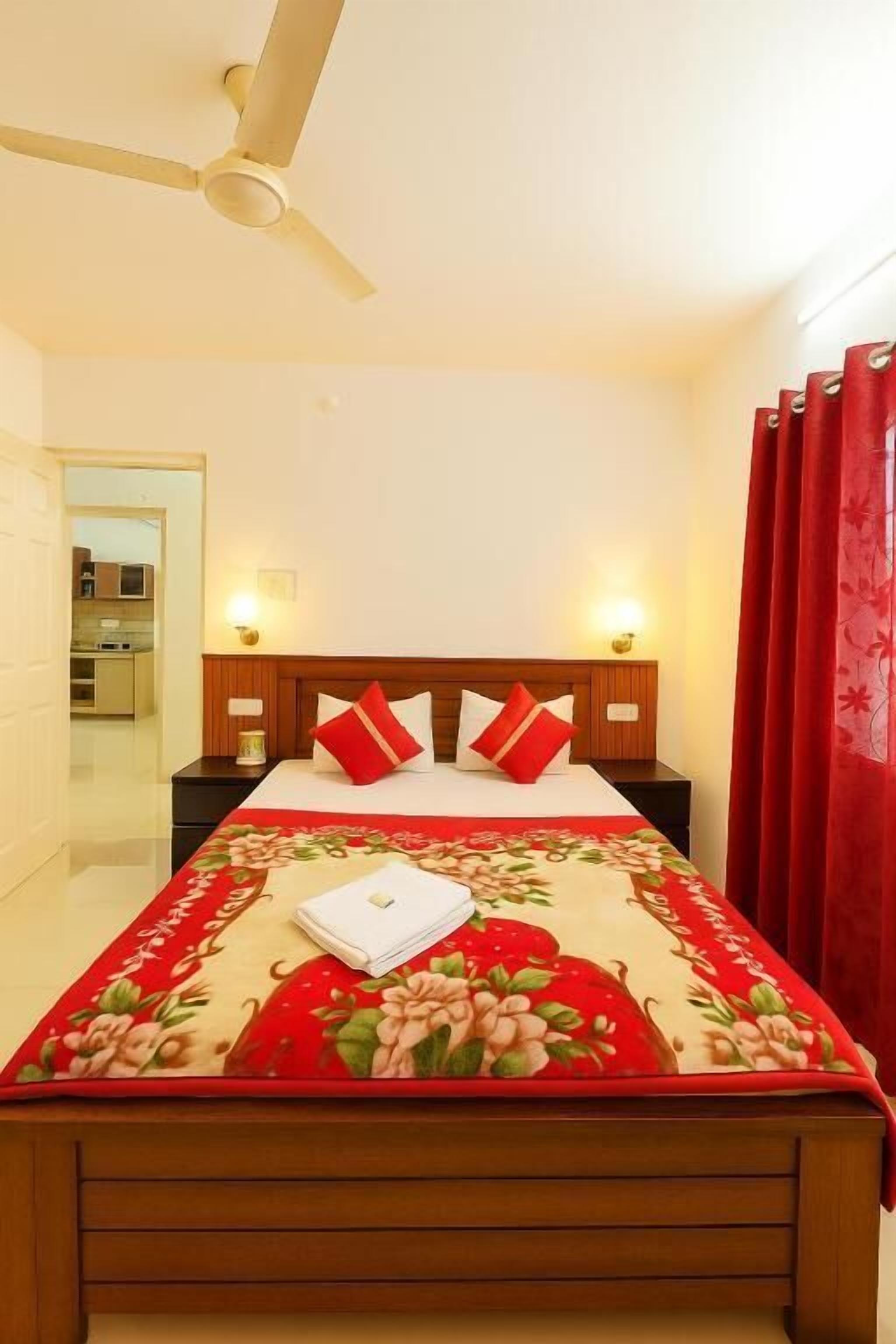 A bedroom with a bed, a ceiling fan, and a red curtain.