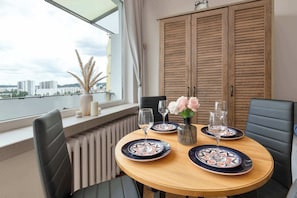 A dining table with plates, glasses, and a vase with flowers. - Cozy apartment with a balcony | Pets welcome (Gdańsk)