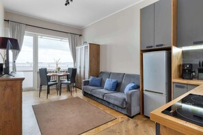 A modern living room with a sofa, dining area, and kitchen. - Cozy apartment with a balcony | Pets welcome (Gdańsk)