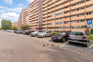Um estacionamento de vários andares com carros estacionados em vagas demarcadas, sinal de limite de velocidade e vaga de estacionamento para deficientes.