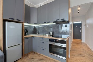A modern kitchen with grey cabinets, a stainless steel refrigerator, an oven, and a wooden countertop. - Cozy apartment with a balcony | Pets welcome (Gdańsk)