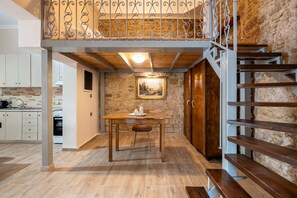 A kitchen with wooden flooring, a dining table, and a staircase with wooden steps. - Absinthia Legacy Country House with Shared Garden, Wi-Fi and Air Conditioning (Soroni)