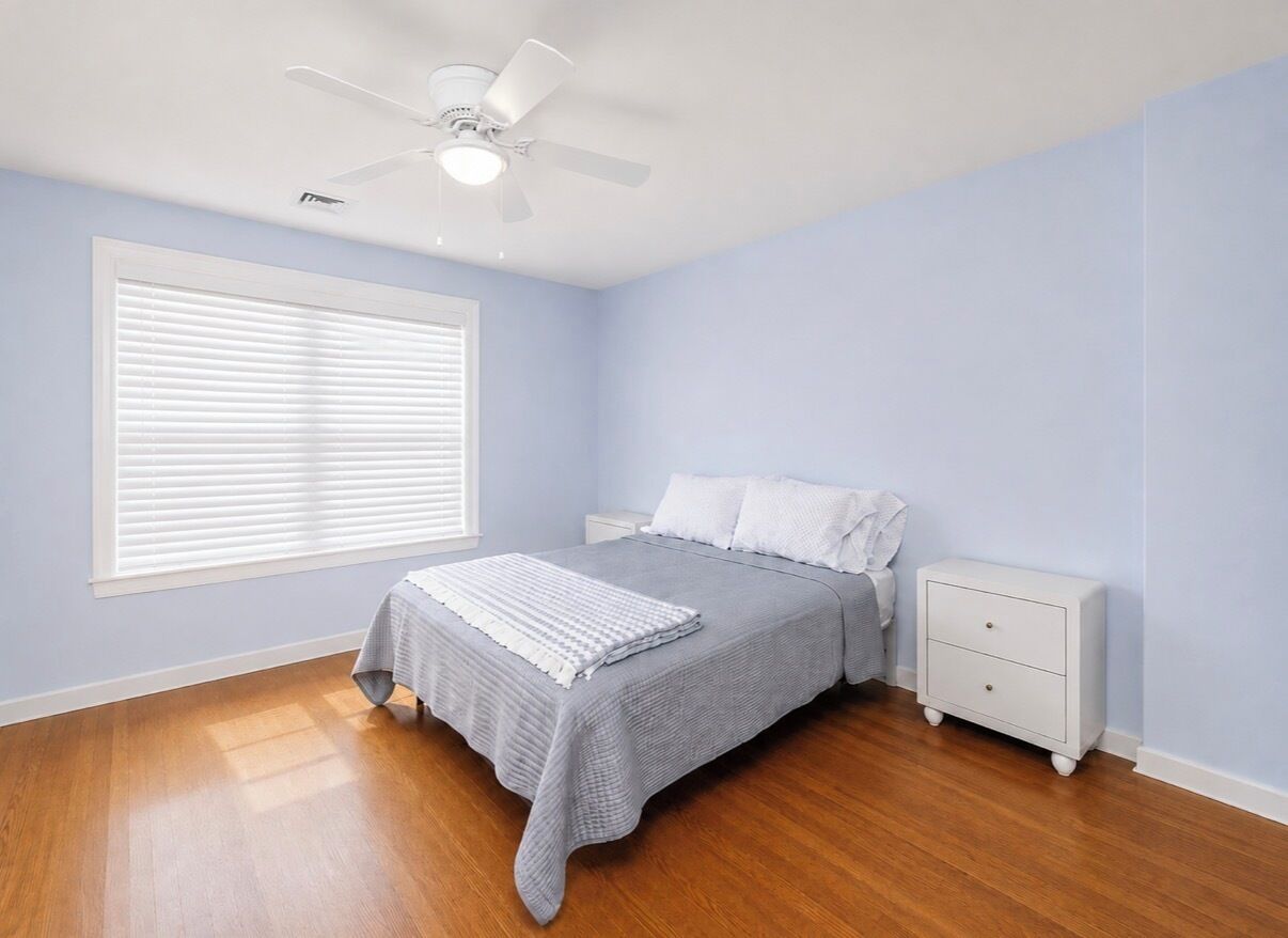 A bedroom with a bed, nightstands, a ceiling fan, and a window with blinds.