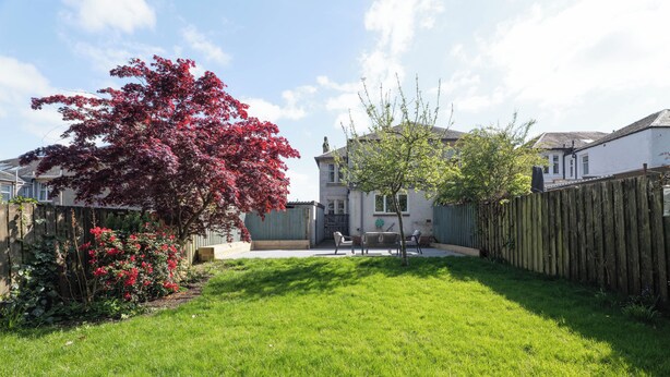 A backyard with a lawn, a wooden fence, and a house in the background. - Spacious 4BR - Private driveway & Garden (Rutherglen)