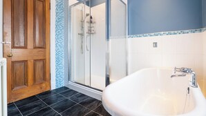 A bathroom with a wooden door, a glass shower enclosure, and a white bathtub. - Spacious 4BR - Private driveway & Garden (Rutherglen)
