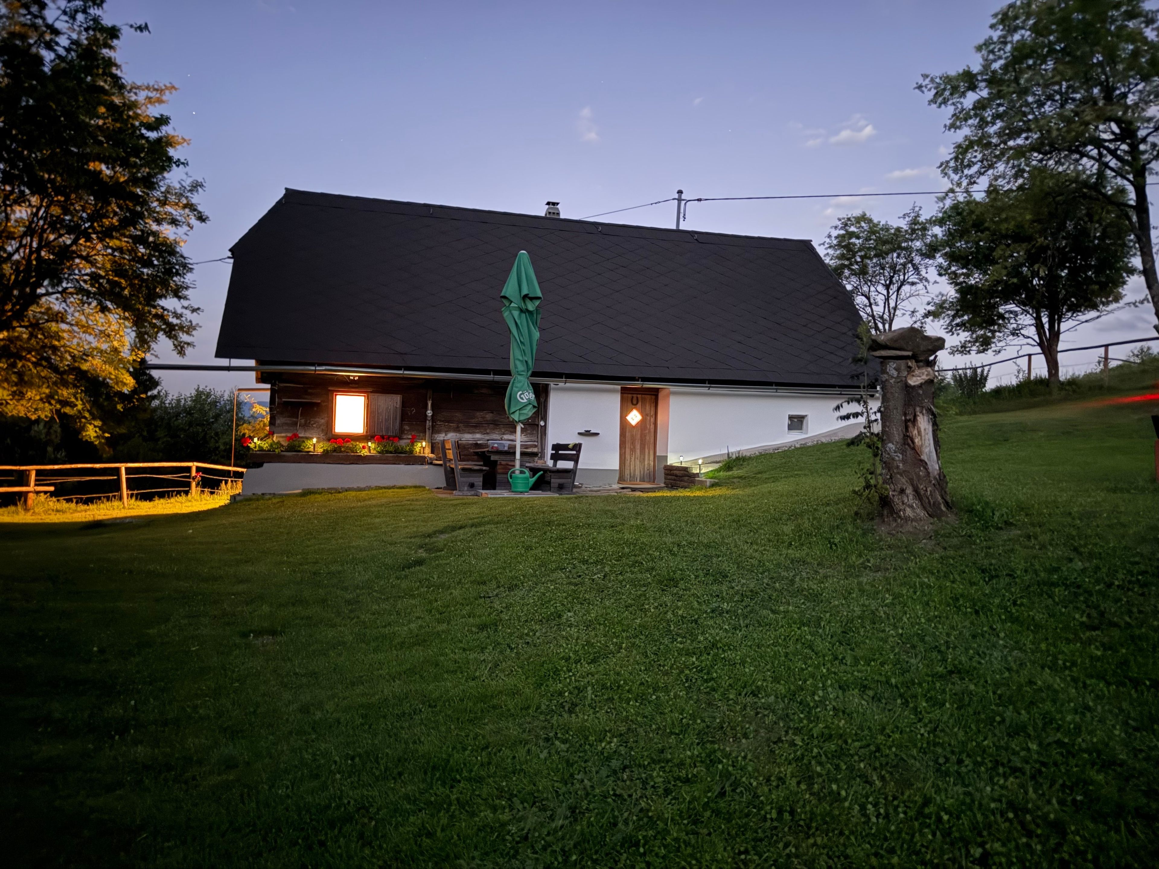 A building with a dark roof, a green umbrella, and a well-maintained lawn.