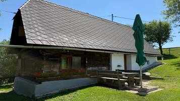 Een landelijk gebouw met een schuin dak, een houten veranda en een groene parasol.