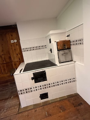 A kitchen with white tiled walls, a black countertop, and a wooden cabinet.