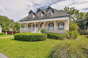 A two-story house with a covered porch, a small garden, and a pathway leading to the house. - Beautiful home in the Pier Village! Close to Beach, Room for Everyone! (Saint Simons Island)