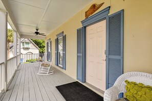 A covered porch with a ceiling fan, a white rocking chair, and a door with blue shutters. - Beautiful home in the Pier Village! Close to Beach, Room for Everyone! (Saint Simons Island)