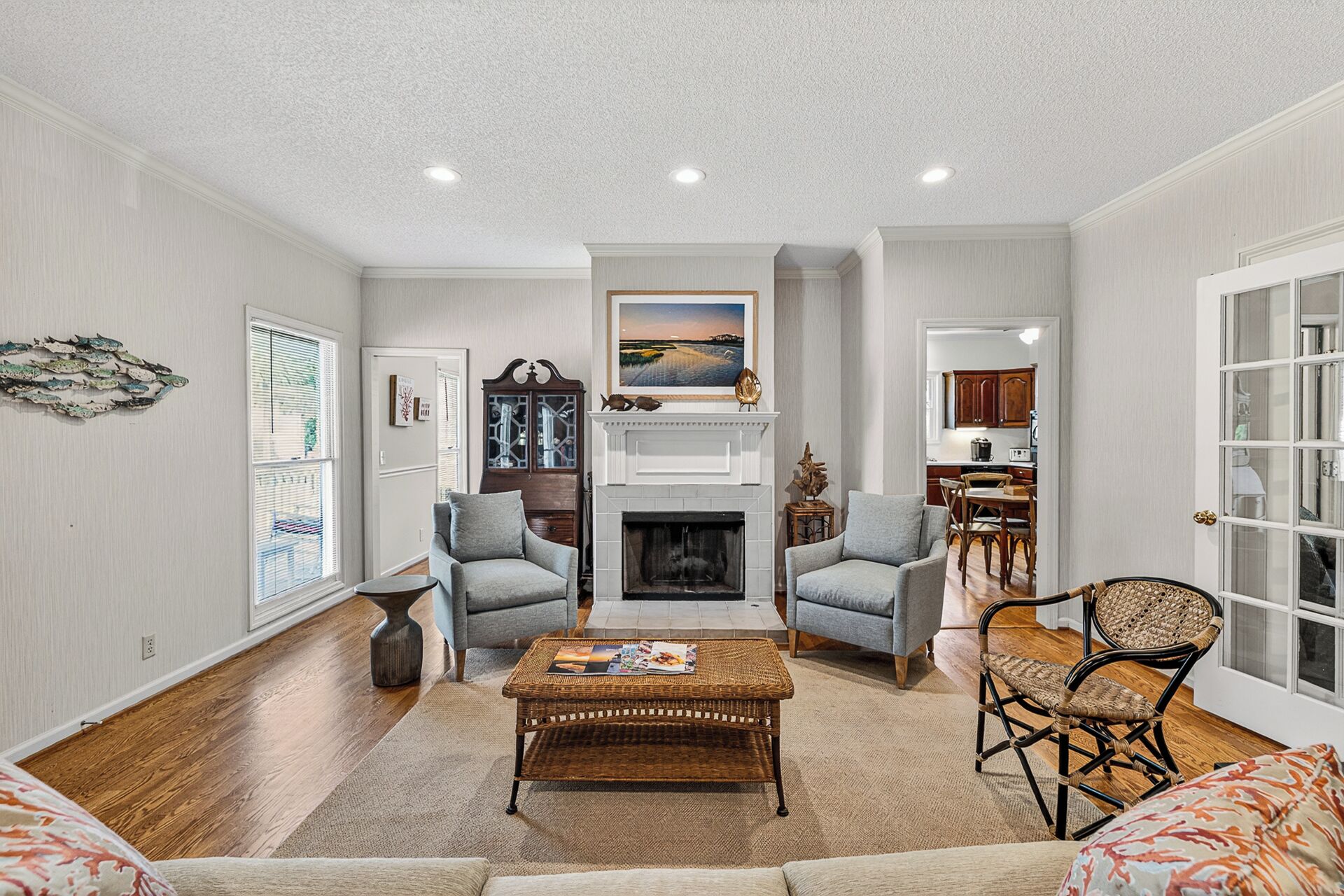 A living room with a fireplace, two armchairs, a coffee table, and a dining area with wooden chairs.