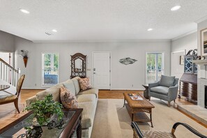 A spacious living room with a sofa, armchair, and a fireplace. - Beautiful home in the Pier Village! Close to Beach, Room for Everyone! (Saint Simons Island)