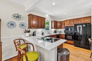 A kitchen with wooden cabinets, a central island, and a stainless steel refrigerator. - Beautiful home in the Pier Village! Close to Beach, Room for Everyone! (Saint Simons Island)
