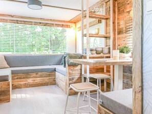 A cozy cabin interior with a wooden interior, a built-in bench, a table with stools, and a window with blinds. - STOERbuiten Mar Y Sierra (Stacciola di San)