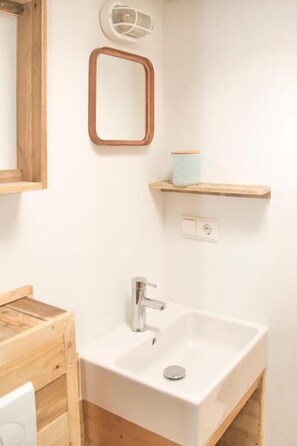 A bathroom with a white sink, wooden vanity, and a mirror. - STOERbuiten Mar Y Sierra (Stacciola di San)