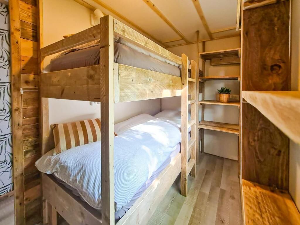 A bunk bed room with wooden walls and shelves.