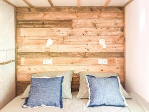 A bedroom with a wooden headboard, two bedside lamps, and two pillows. - STOERbuiten Mar Y Sierra (Stacciola di San)