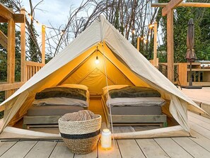 A tent with two beds, a lantern, and a woven basket on a wooden deck. - STOERbuiten Mar Y Sierra (Stacciola di San)