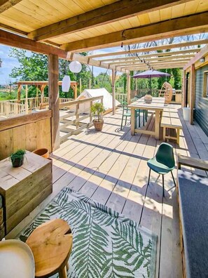 An outdoor wooden deck with a table and chairs, a green chair, and a small table with a plant. - STOERbuiten Mar Y Sierra (Stacciola di San)