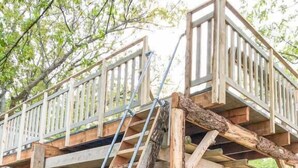 Una terraza de madera con una escalera que lleva a un espacio cubierto.