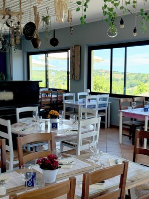 A dining area with tables set for meals, chairs, and hanging plants. - STOERbuiten Mar Y Sierra (Stacciola di San)