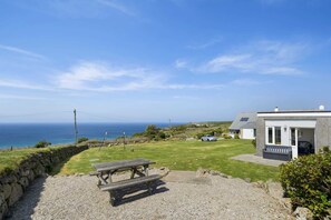 A coastal property with a grassy lawn, a picnic table, and a view of the sea. - Kitticarn, Panoramic Sea Views, Garden, Parking (Sennen)