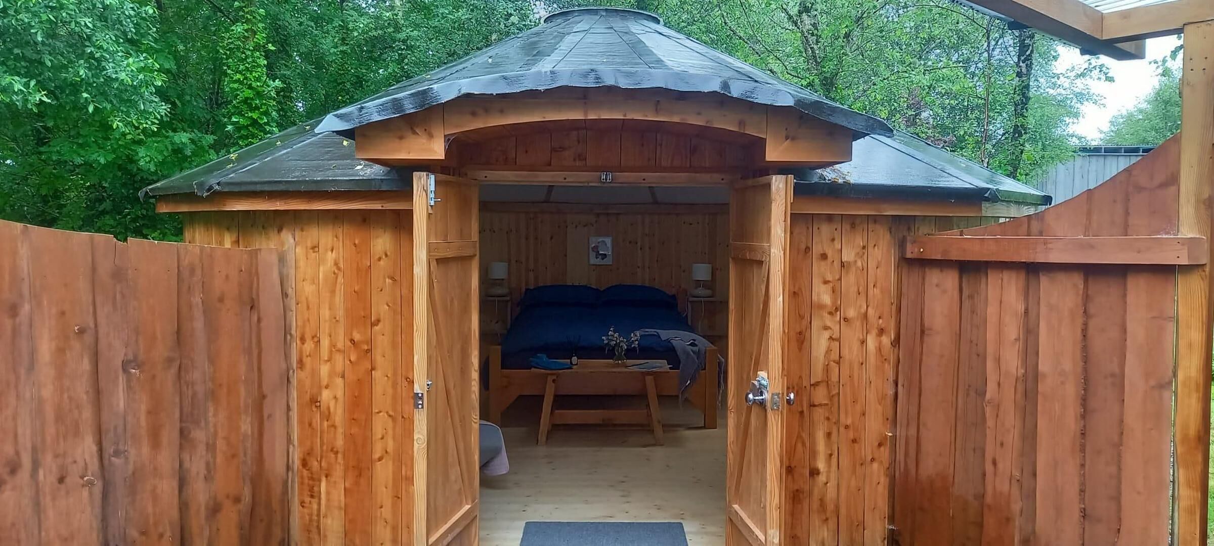 Una baita di legno con un letto, un tavolino e una sedia.
