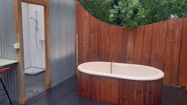 Un baño con ducha, bañera y pared de madera.