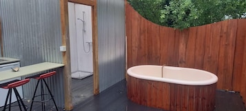 Un baño con ducha, bañera y pared de madera.