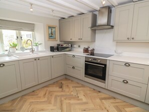 Eine moderne Küche mit hellen Schränken, einem eingebauten Ofen und einem Holzboden mit Fischgrätmuster.
