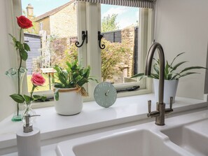A bathroom with a window, a sink, a clock, and potted plants. - 2 The Gardens (Lechlade)