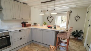 A kitchen with a herringbone floor, a dog, and heart-shaped decorations on the wall. - 2 The Gardens (Lechlade)