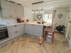 A kitchen with a herringbone floor, a dog, and heart-shaped decorations on the wall. - 2 The Gardens (Lechlade)