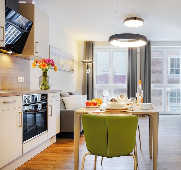 Et moderne køkken med spiseplads, en grøn stol og et bord dækket til måltid.