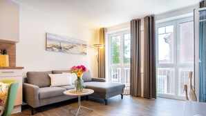 Una sala de estar moderna con un sofá gris, una mesita redonda con un florero y un cuadro en la pared.