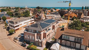 Zona residencial con una mezcla de arquitectura moderna y tradicional, incluyendo un edificio con paneles solares y una grúa al fondo.
