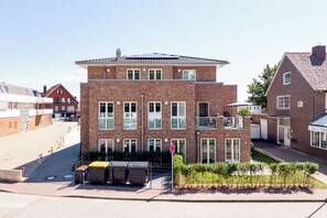 En toetages boligbygning med facade i mursten, flere vinduer og en lille balkon.