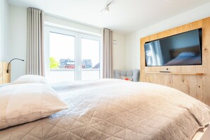 Ein Hotelzimmer mit einem großen Bett, einem wandmontierten Flachbildfernseher und einer Glastür zu einem Außenbereich.