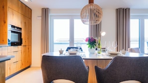 Een moderne keuken met houten kastjes, een inbouwoven en een eethoek met een tafel gedekt voor twee personen.