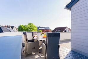 Eine Dachterrasse mit Tisch, Stühlen und Blick auf die umliegenden Gebäude.