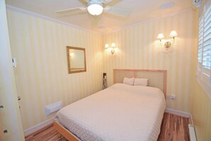 A bedroom with a bed, a ceiling fan, wall-mounted lamps, and a radiator. - Beachcrest 8 - Ocean City, MD (Ocean City)
