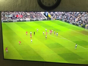 Ein Fernsehbildschirm zeigt ein Fußballspiel mit einer Anzeigetafel, die den Spielstand 0:2 anzeigt.