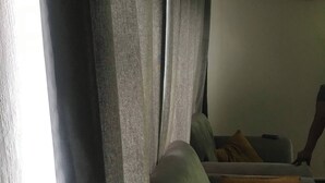 Una sala de estar con un sofá, una mesa de centro y una ventana con cortinas.