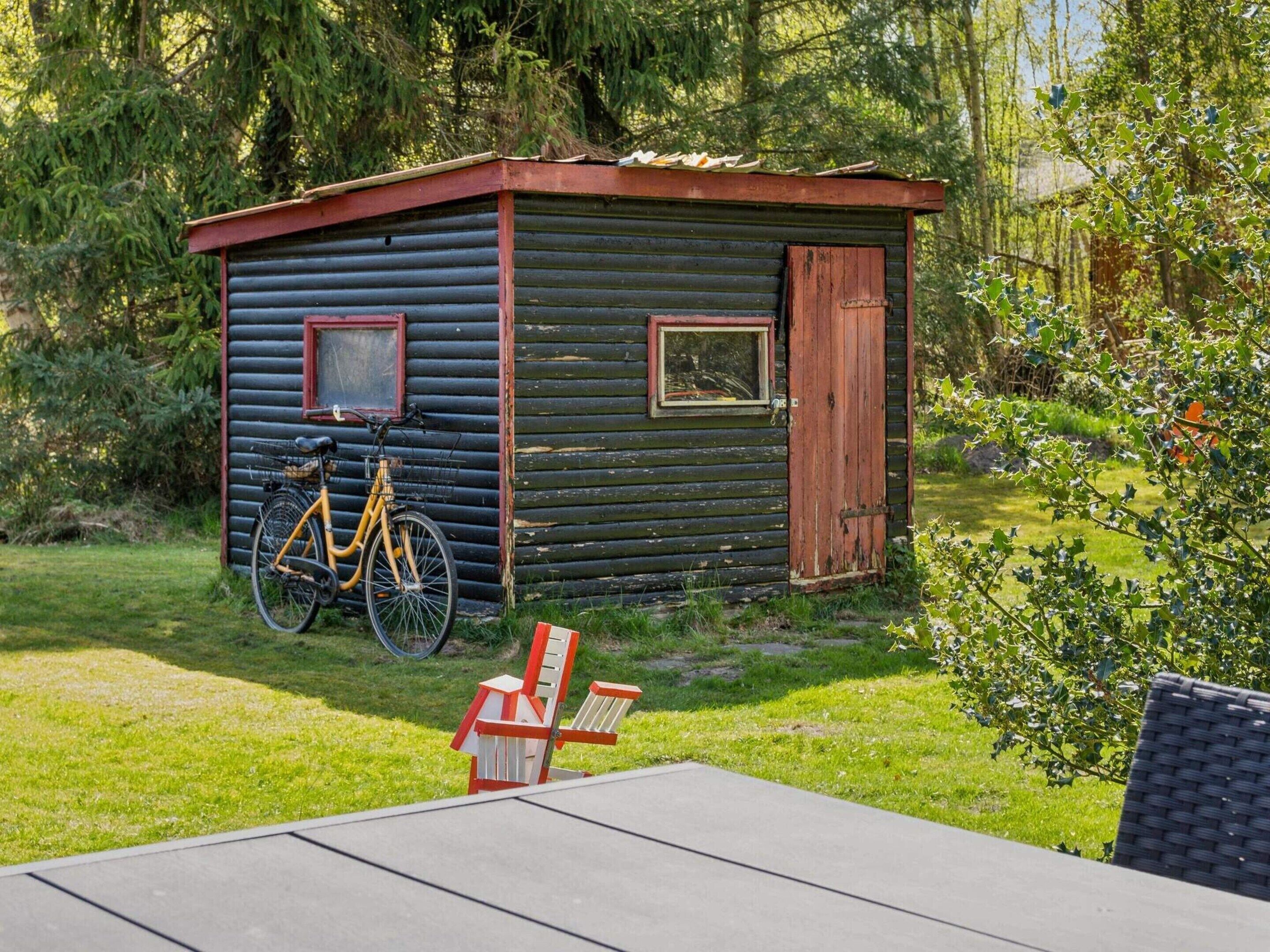 A small cabin with a bicycle parked outside, a wooden door, and a window.