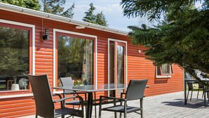 A wooden deck with a table and chairs, a window, and a door. - 5 Star Holiday Home in Gedser (Gedser)